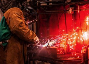 A welder is welding two pieces of metal with sparks flying